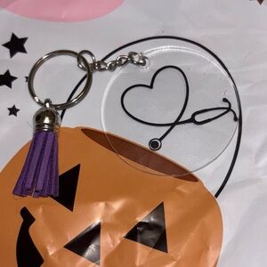 clear acrylic keychain with a purple tassel and a stethoscope heart design